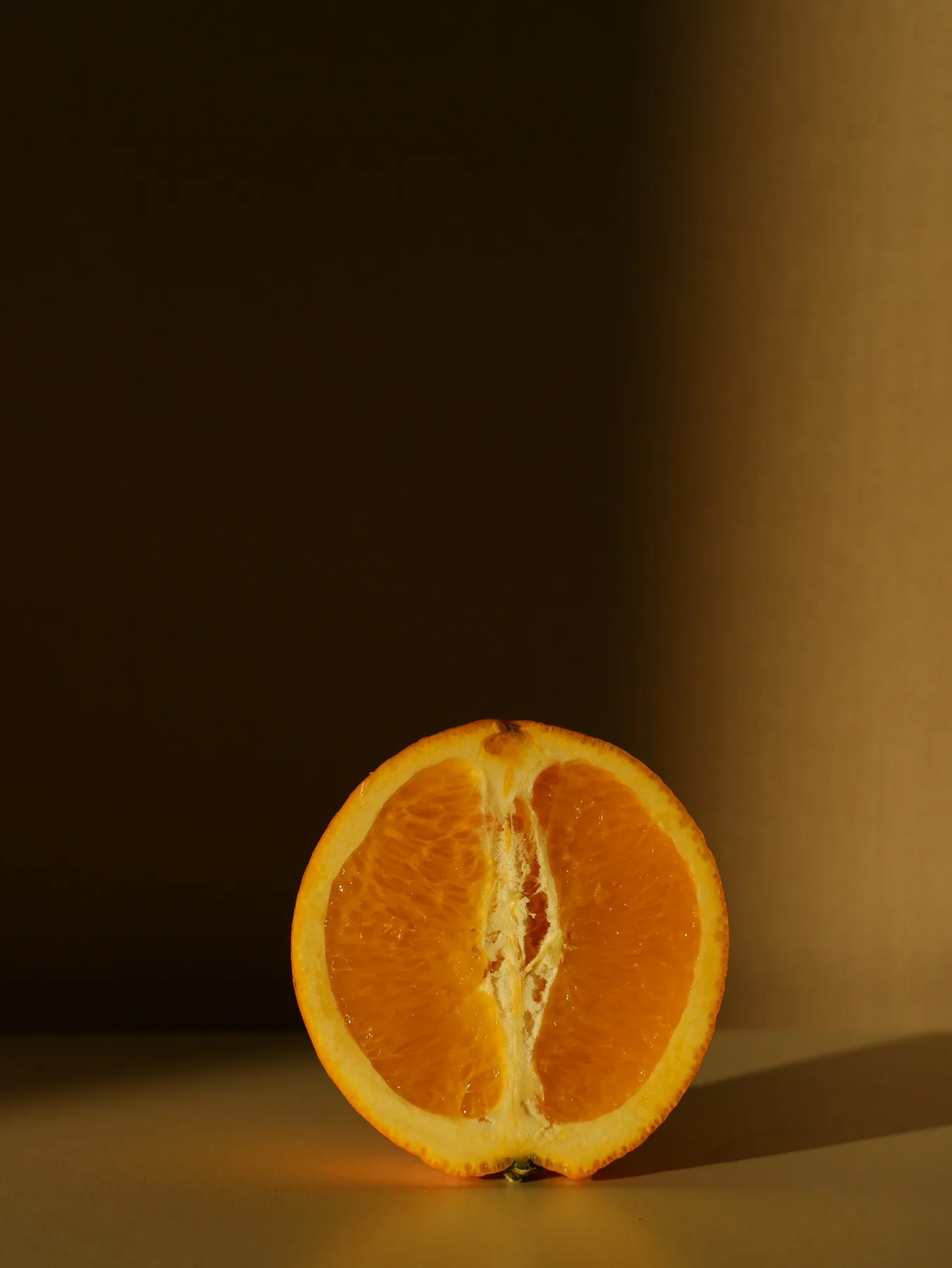 Halved orange lit warmly against a shadowed backdrop.